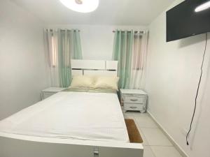 a small bedroom with a white bed and green curtains at Santiago Monumental Area Cozy 3 bedrooms Apartment for 7 peoples - transportation 24 hours-9 in Santiago de los Caballeros