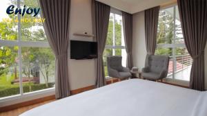Alulu Luxury Residence - Four Bedroom Villa في Cikundul: غرفة نوم بسرير وكرسيين وتلفزيون