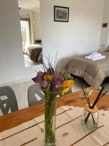 eine Vase mit Blumen auf einem Tisch im Wohnzimmer in der Unterkunft Apart Los Algarrobos in Marcos Juárez