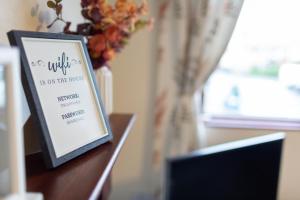 a picture frame on a table with a vase of flowers at Adrian House, near Hospital, easy parking + garden in Carlisle