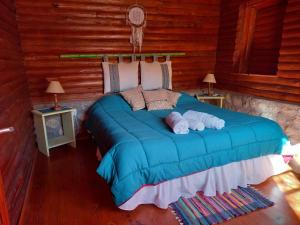 um quarto com uma cama azul num chalé de madeira em Mainame Traslasierra em Los Hornillos