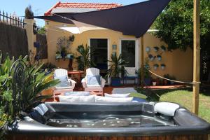 a hot tub in a yard with chairs and an umbrella at Geronimo Guest House Belém in Lisbon