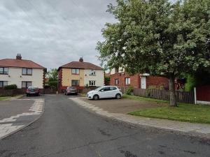 une voiture blanche garée sur le côté d'une rue dans l'établissement Adrian House, near Hospital, easy parking + garden, à Carlisle