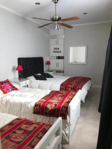 Un dormitorio con tres camas y un ventilador de techo. en Alquiler temporario Tandil LAS PALMERAS I, en Tandil