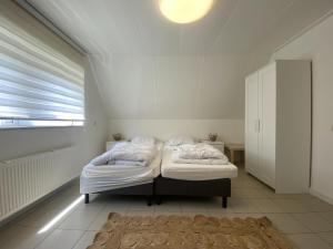 1 dormitorio blanco con 2 camas y ventana en Catharina, en Stevensweert