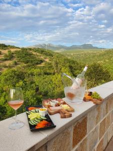 ein Tablett mit Essen und ein Glas Wein auf einem Felsvorsprung in der Unterkunft Djukic Winery in Podgorica