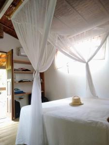 a bed with a white canopy with a hat on it at Casa Marcela in Barra Grande