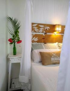 um quarto com uma cama e um vaso de flores sobre uma mesa em Casa Marcela em Barra Grande