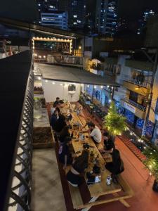 un grupo de personas sentadas en mesas en un restaurante por la noche en La Familia Hostel en Medellín