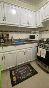 - une cuisine avec des placards blancs et un tapis au sol dans l'établissement L&Y Punta Cana Beach Apartament, à Punta Cana