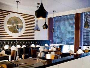um restaurante com mesas e cadeiras e um relógio na parede em Artto Hotel em Glasgow