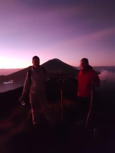 deux hommes debout au sommet d'une montagne au coucher du soleil dans l'établissement Bunbulan Hill Hostel and Cottage, à Kintamani