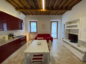 cocina y sala de estar con mesa y sofá rojo en Sasso Grosso House, en Ronciglione