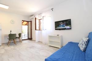 sala de estar con cama azul y TV en la pared en Apartments by the sea Mandre, Pag - 6284 en Kolan