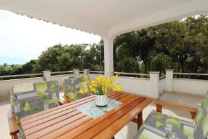 a porch with a wooden table and chairs on a balcony at Apartments by the sea Mandre, Pag - 6284 in Kolan