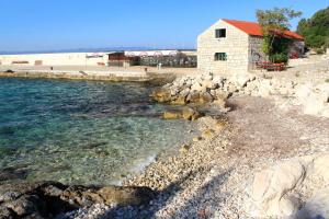a building on a rocky beach next to the water at Holiday house Lastovo - 8289 in Lastovo