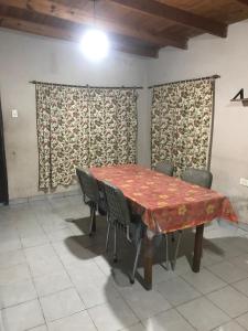 Un comedor con mesa y sillas y cortinas. en Departamentos Sarmiento, en San Luis