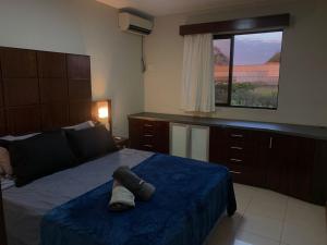 a bedroom with a bed with a blue blanket and a window at Lindo Apart Lake Side com banheira in Brasilia