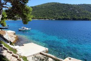 a boat in the water next to a beach at Apartments by the sea Pasadur, Lastovo - 8388 in Lastovo