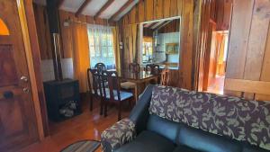 uma sala de estar com um sofá e uma mesa de jantar em Parcela Bemel em Coñaripe