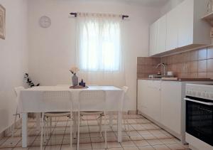 a kitchen with a white table and chairs and a window at Apartments with a parking space Rukavac, Vis - 8496 in Rukavac