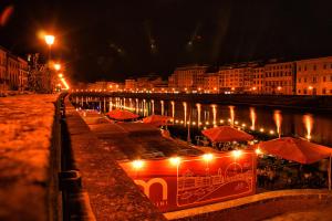 una ciudad iluminada por la noche con mesas y sombrillas en Nice apartment on the riverside, en Pisa