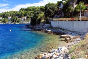 a beach with blue water and a white fence at Apartments by the sea Medvinjak, Korcula - 9268 in Korčula