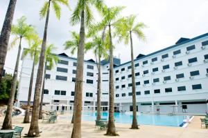 a hotel with palm trees in front of a pool at SWISS AVENUE HOTEL in Sungai Petani