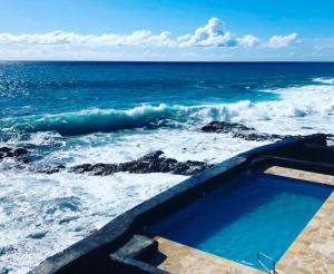 una piscina en la playa con el océano en Kona Tiki Hotel en Kailua-Kona