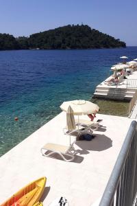 a beach with chairs and umbrellas and the water at Family friendly apartments with a swimming pool Smokvica, Korcula - 9161 in Smokvica