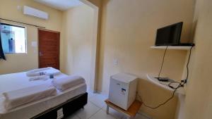 1 dormitorio con 1 cama y TV en la pared en Pousada Nossa Senhora Das Dores en Maragogi