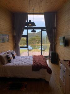 a bedroom with a bed and a large window at Estalagem Santa Clara in Urubici