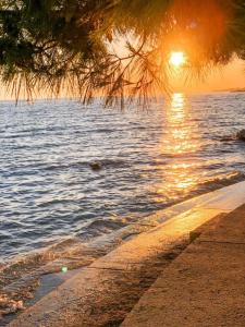 a beach with the sun setting over the water at APARTMENT SECRET GARDEN 3 in Zaton