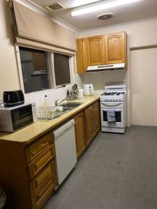 a kitchen with wooden cabinets and white appliances at Doncaster Westfield Home Stay in Doncaster