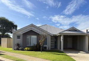 a house with a grass yard in front of it at By the Beach in Broadwater