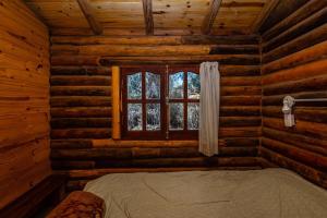 a bedroom in a log cabin with a bed and a window at Posada Arco Iris in San Marcos Sierras