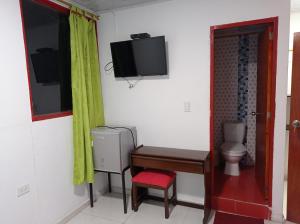 a room with a desk and a toilet and a television at Hotel Acuarius in Cúcuta
