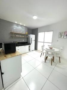 uma cozinha branca com uma mesa e piso em azulejo branco em Casa em Peroba/Maragogi 100m da Praia em Ponta do Mangue