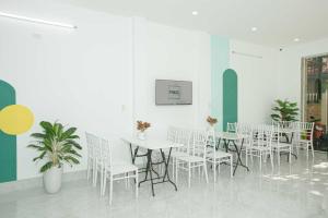 a dining room with white tables and white chairs at Pao Hotel in Hue