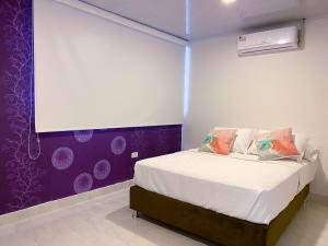 1 dormitorio con 1 cama con pared morada en OCEANA HOTEL, en San Andrés