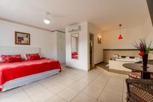 a bedroom with a red bed and a bathroom at Hotel Miratlantico Búzios in Búzios