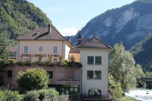 a large white building with a balcony next to a river at Cit'Hôtel Le National in Cluses