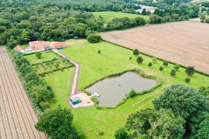an aerial view of a farm with a pond in a field at Cottage In Norfolk Sleeps 23 - Private Pool, Fishing Lake, Hot Tub Ref 99008sc in Hockham