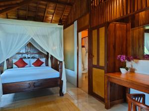 a bedroom with a canopy bed and a desk at MUNDUK RETREAT - Pondok Pekak Lelut in Munduk