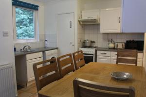 eine Küche mit einem Holztisch, Stühlen und einem Waschbecken in der Unterkunft 2 Bedroom Flat in Luton City Centre in Luton