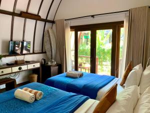 a bedroom with two beds and a tv and a window at The Yoga Garden in Gili Trawangan