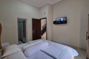 a bedroom with a bed with a tv on the wall at Oemah Wisata RinginSari -Full House, 5 Bed Rooms- in Kalasan +40 photos