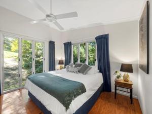 a bedroom with a large bed and windows at Mavis's Cabins @ Mt Warning in Uki