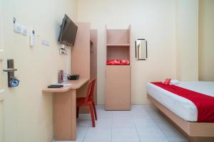 a bedroom with a bed and a desk with a computer at RedDoorz Syariah near Taman Siring 2 in Benuaanyar