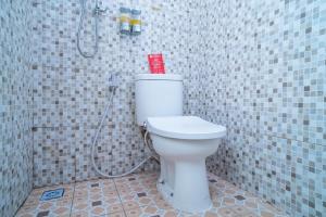 a bathroom with a white toilet with a shower at RedDoorz Syariah near Taman Siring 2 in Benuaanyar